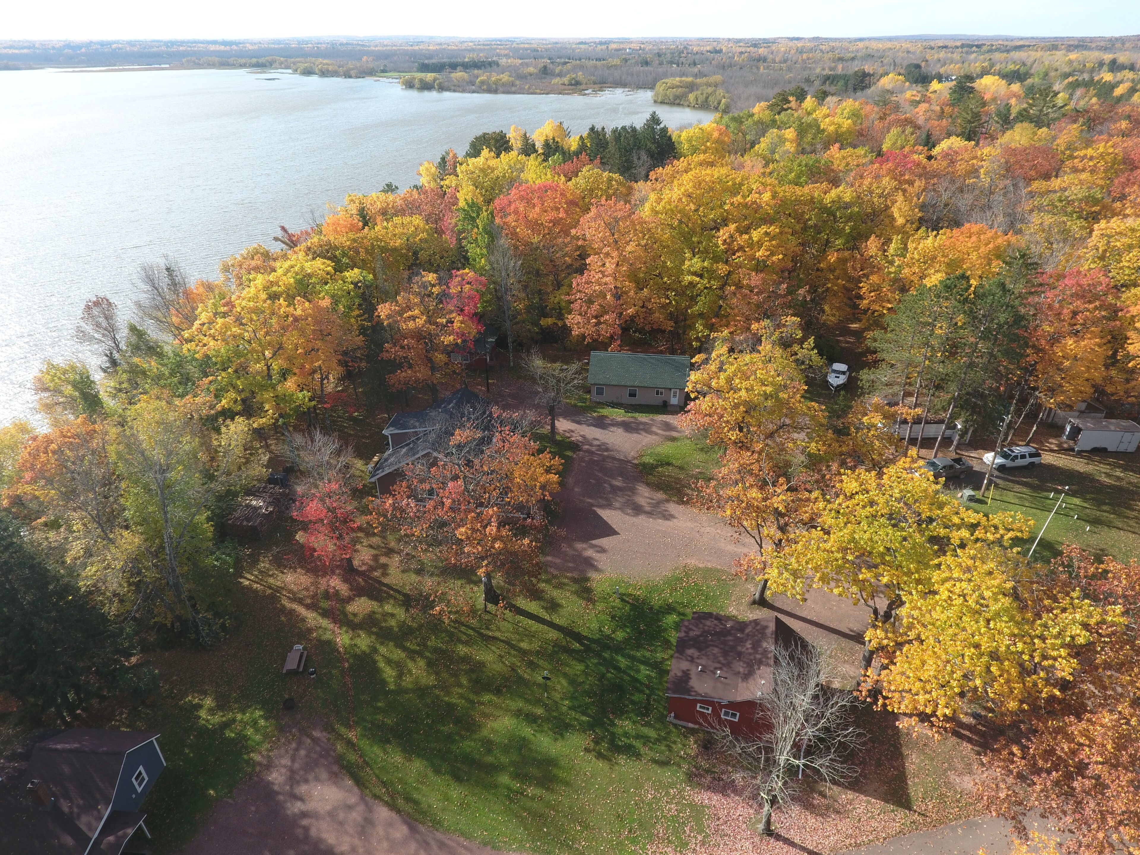 An aerial view of a lakeside property with a house, a boat, and a dock.
