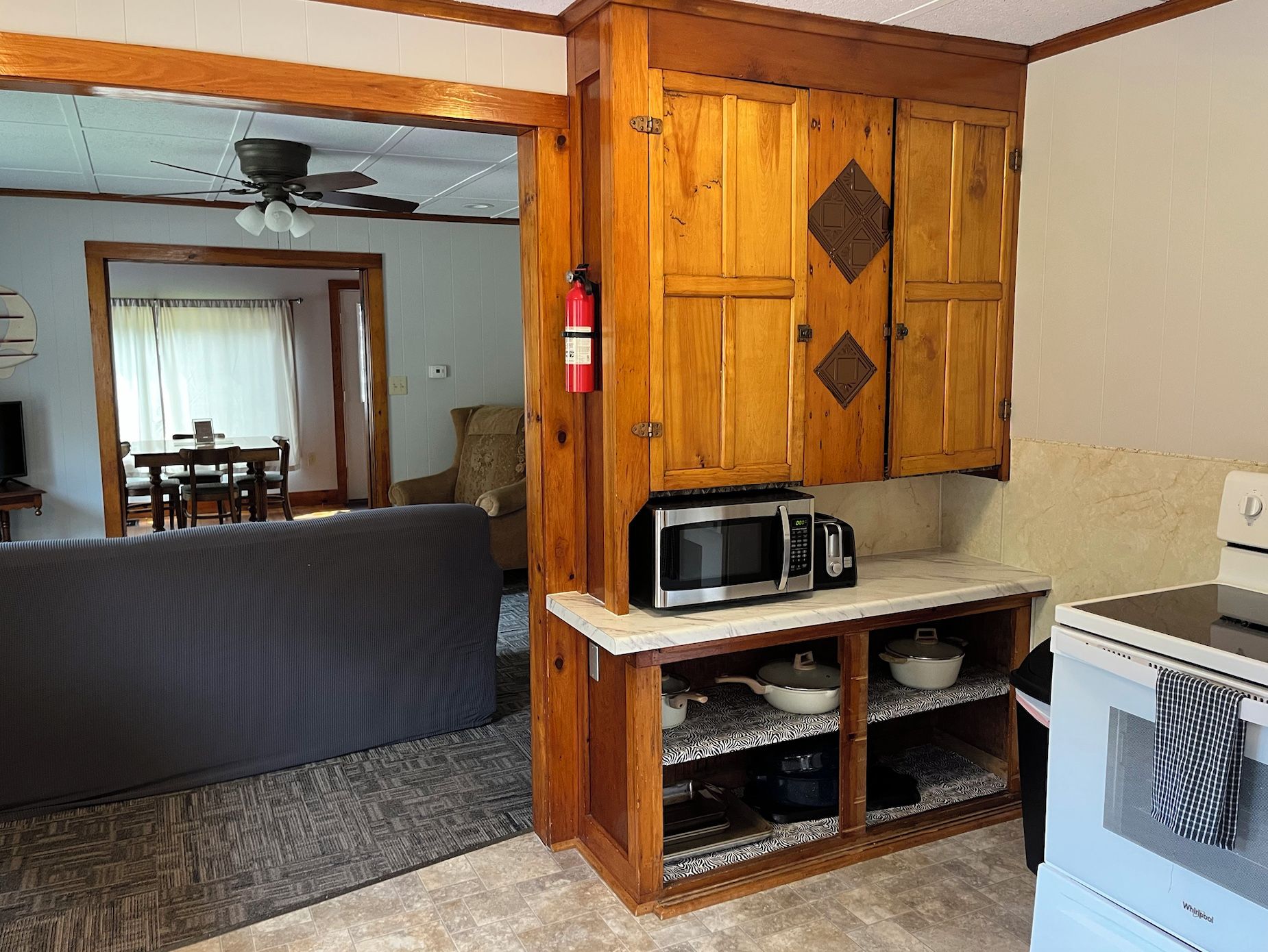 A compact kitchen with wooden cabinets, a microwave, and a stove.