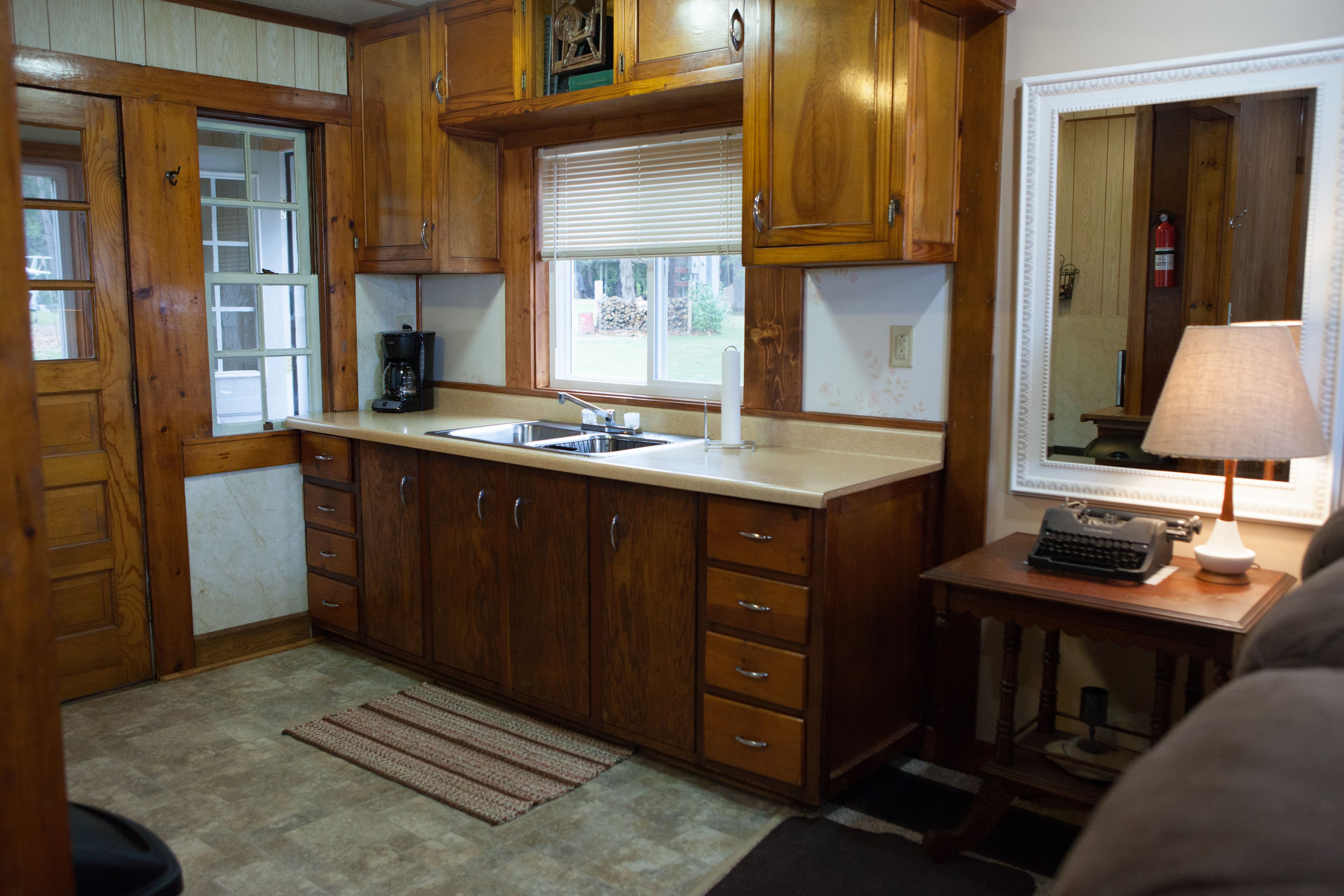 A kitchen with wooden cabinets, a sink, and a window with blinds.