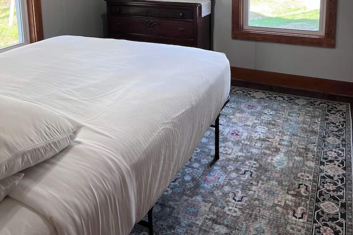 A bedroom with a bed, a dresser, a mirror, and a ceiling fan.