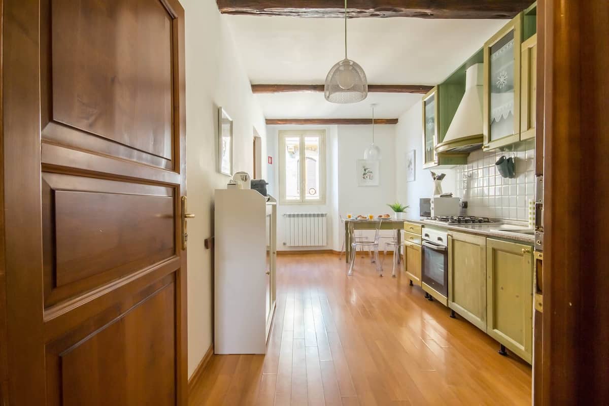 A kitchen with wooden cabinets, a dining table, and a hanging light fixture.