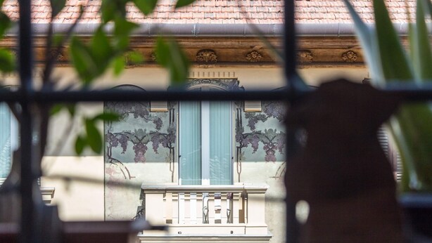 A building facade with a balcony, ornate window frames, and a tiled roof. - Torripa Group - Trastevere (Rome)