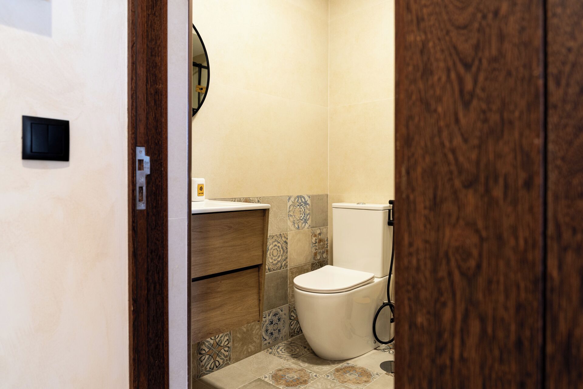 A small bathroom with a toilet, sink, and wooden cabinet.