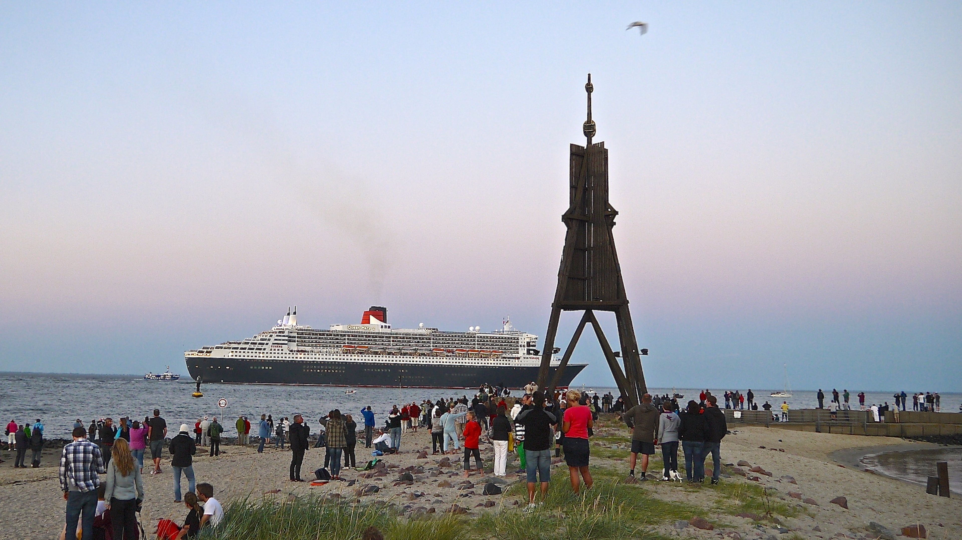 Un gran crucero amarrado en un muelle, con una multitud de personas en la playa.