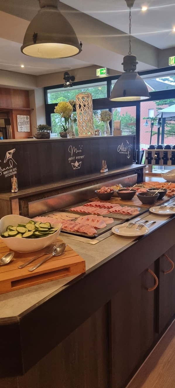 A buffet area with a variety of food options, including sliced meats and a bowl of sliced cucumbers. - Nordsee-Hotel Deichgraf (Cuxhaven)