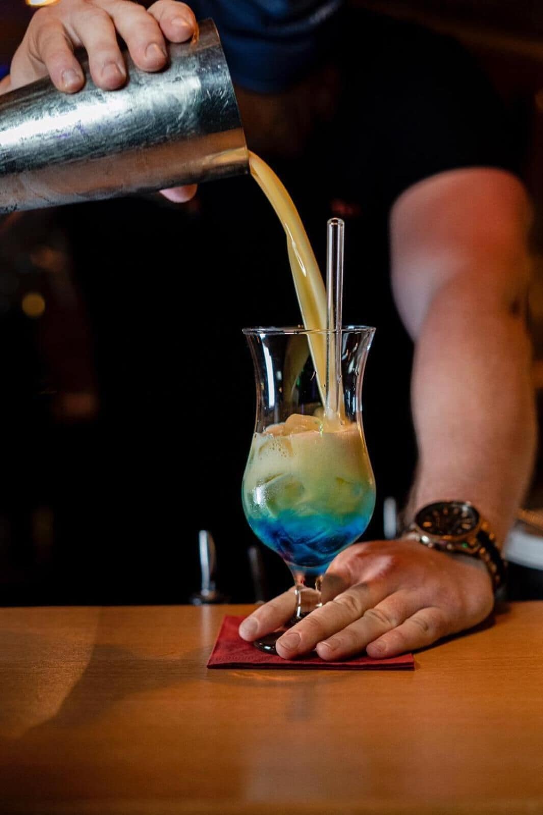 A person pouring a drink into a glass with a straw.