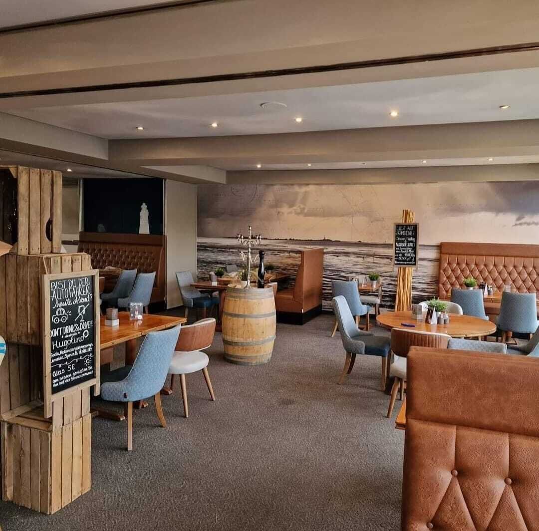 Un restaurante acogedor de ambiente rústico, con mobiliario de madera, un barril grande como elemento central y un menú en la pizarra.