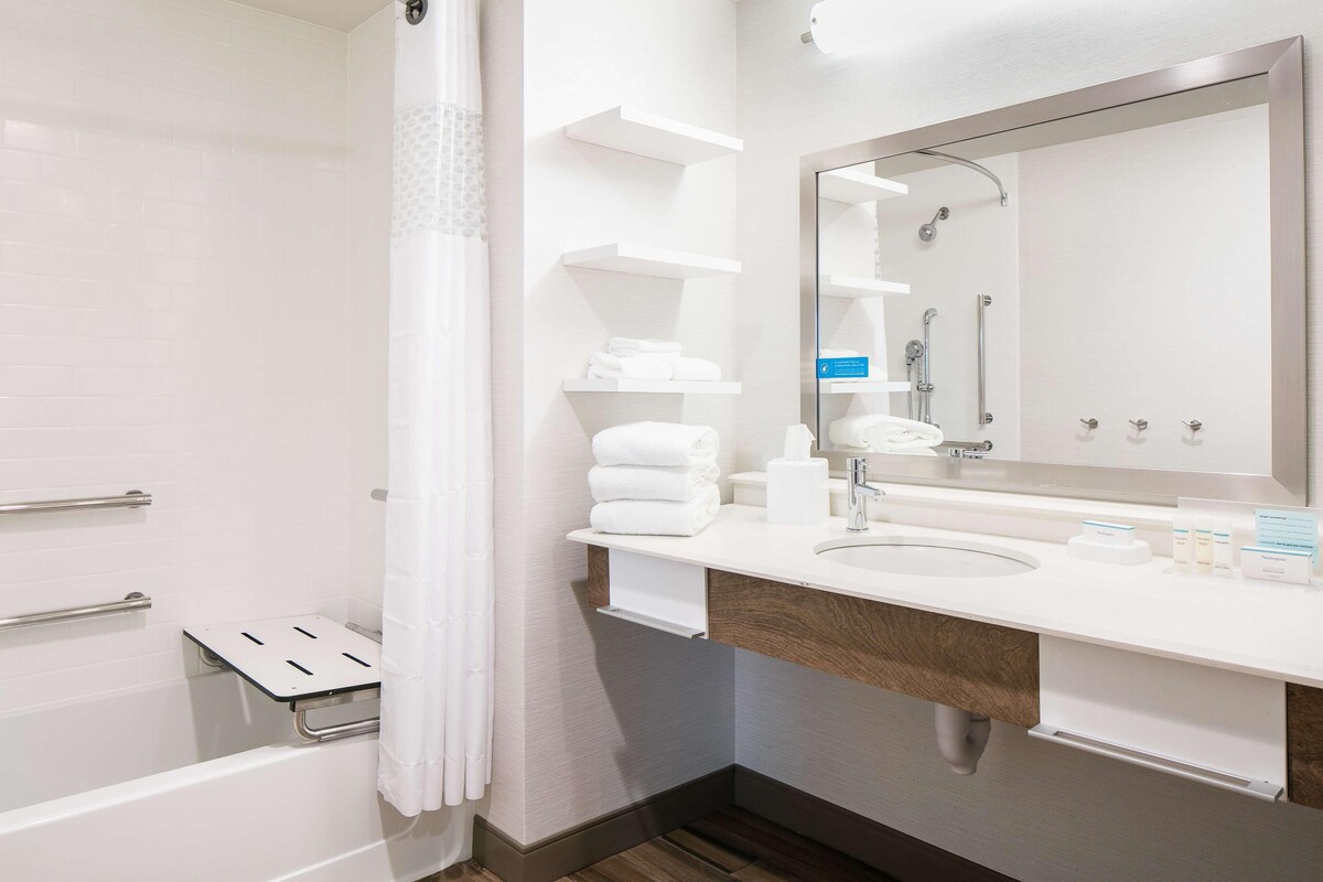 A modern bathroom with a shower, a sink with a mirror, and a towel rack.