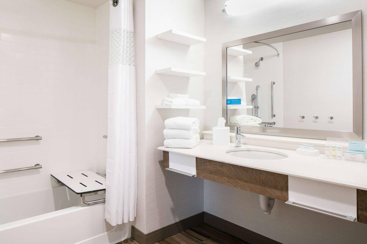 A modern bathroom with a shower, a sink with a mirror, and a towel rack.