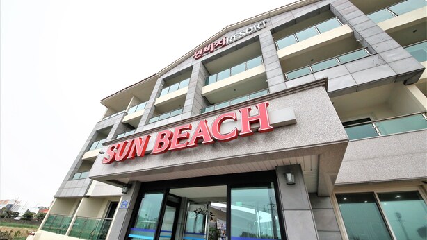 Un immeuble à plusieurs étages dont la façade est ornée d’une grande enseigne indiquant « SUN BEACH ».