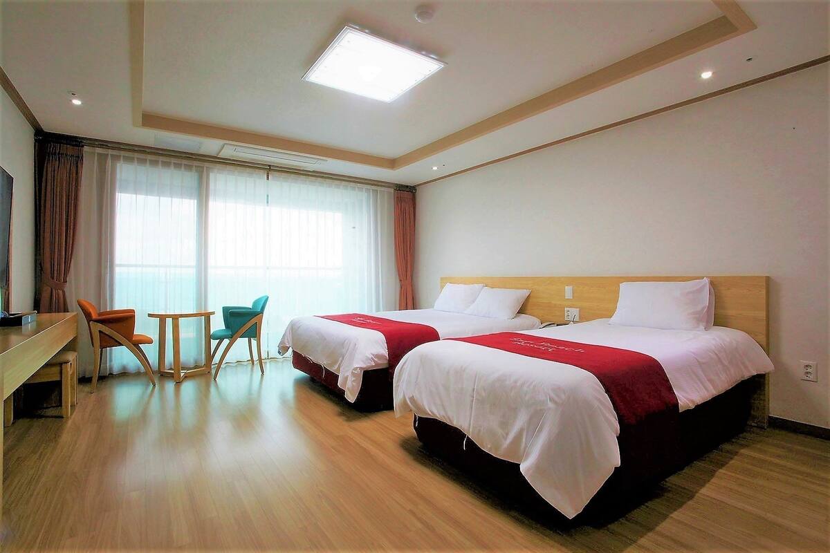 A hotel room with two beds, a desk, and a chair.