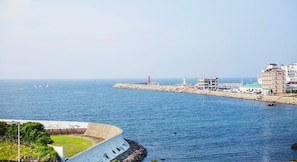 A coastal view with a lighthouse, marina, and buildings along the shore. - Sunbeach Resort (Jeju City)