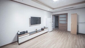 Une chambre à coucher moderne et minimaliste, dotée d’un grand lit, d’une armoire intégrée et d’un téléviseur fixé au mur.