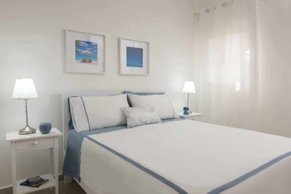 A neatly arranged hotel room with a large bed, two bedside tables with lamps, and two framed pictures on the wall.