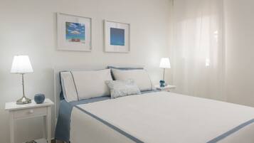 A neatly arranged hotel room with a large bed, two bedside tables with lamps, and two framed pictures on the wall.