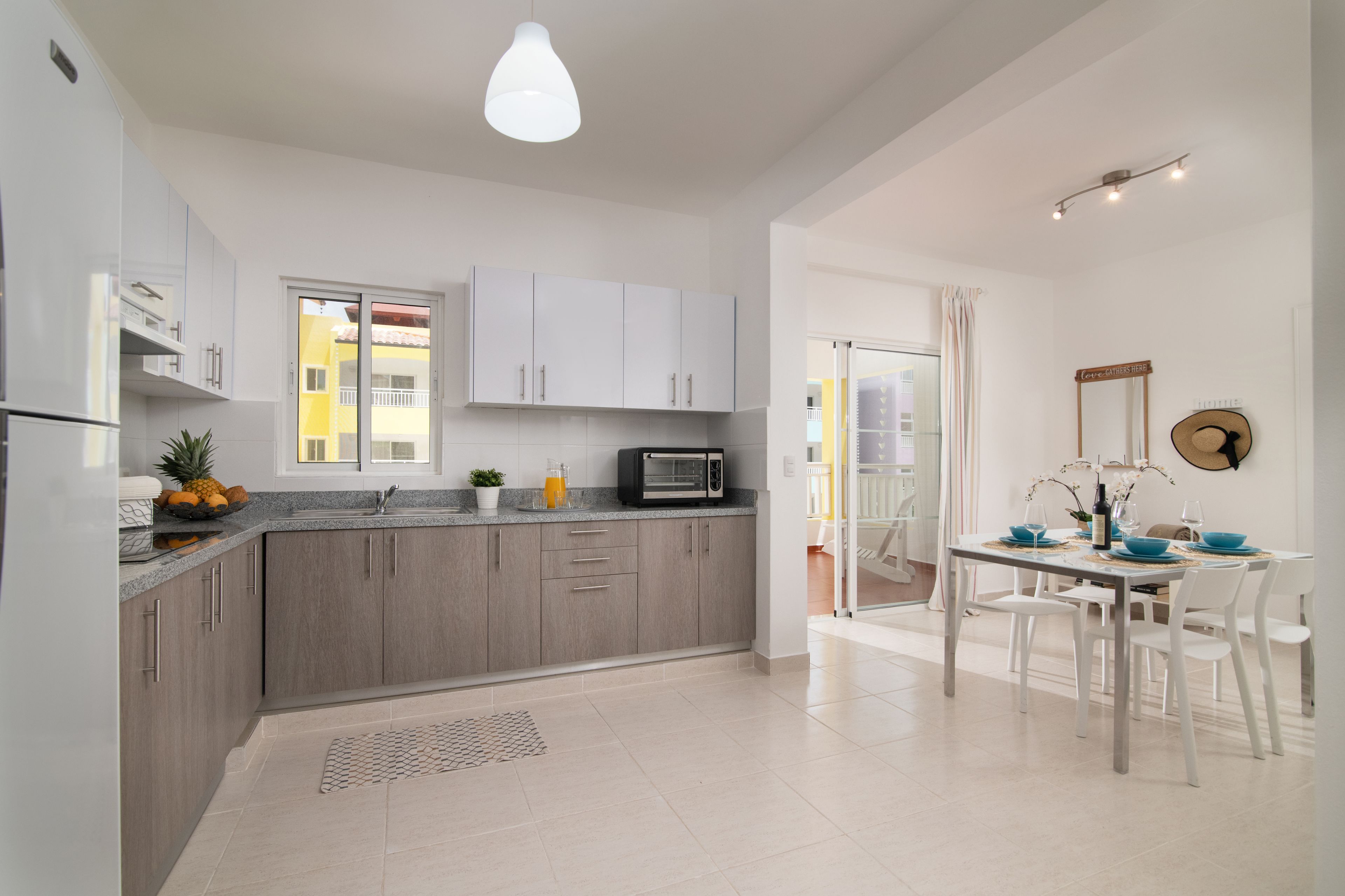 Una cocina moderna con armarios grises, un microondas y un comedor con una mesa preparada para cuatro.