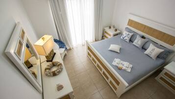 Une chambre bien rangée, avec un lit, des tables de chevet, une commode, un miroir et une fenêtre avec des rideaux.