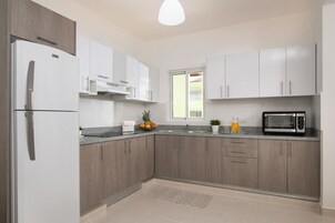 A modern kitchen with a refrigerator, microwave, and granite countertop.