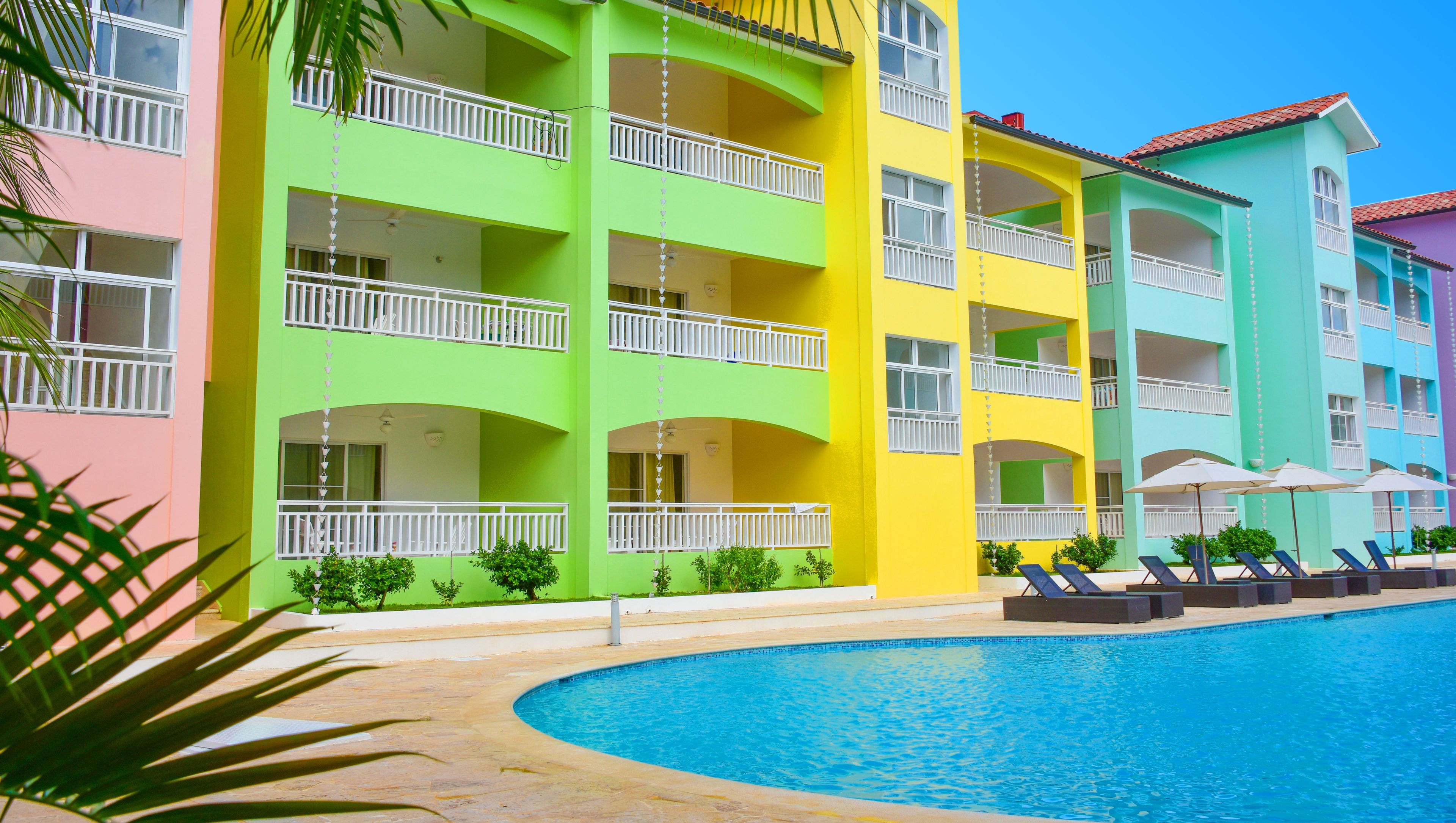 A multi-story hotel with balconies and a swimming pool.