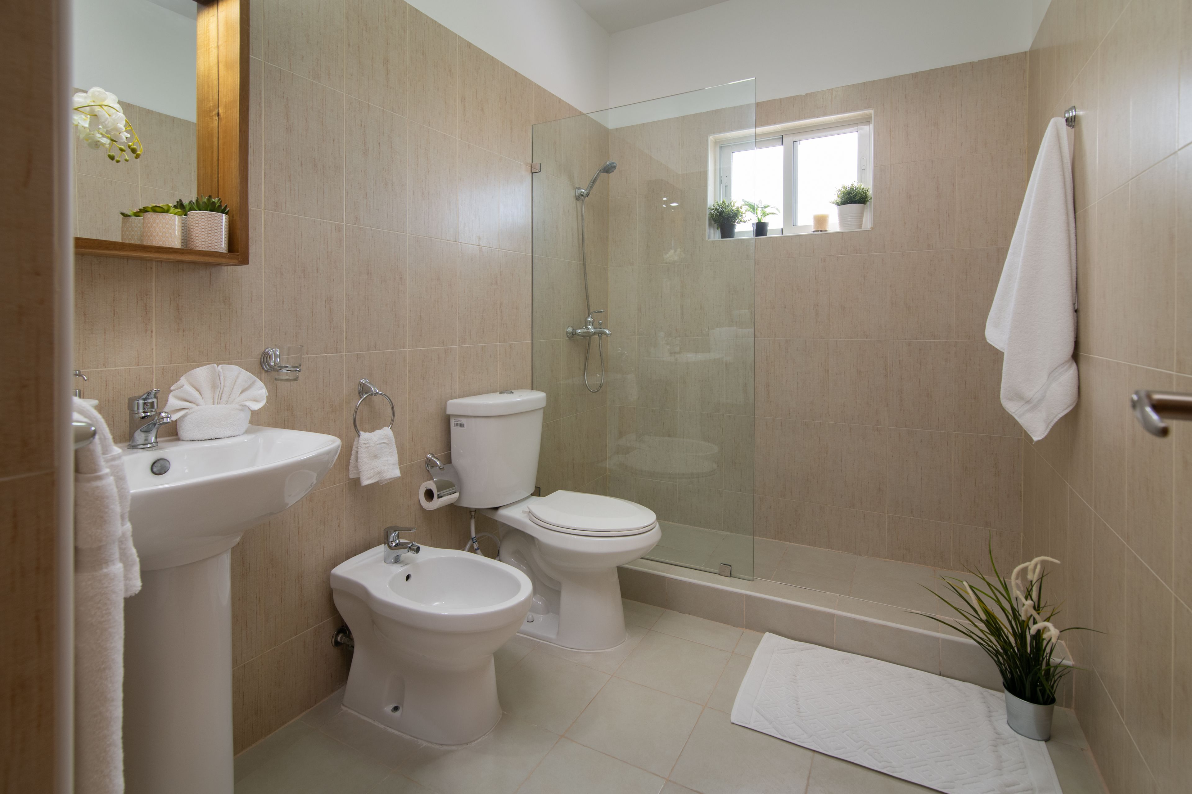 A modern bathroom with a sink, bidet, toilet, and glass-enclosed shower.