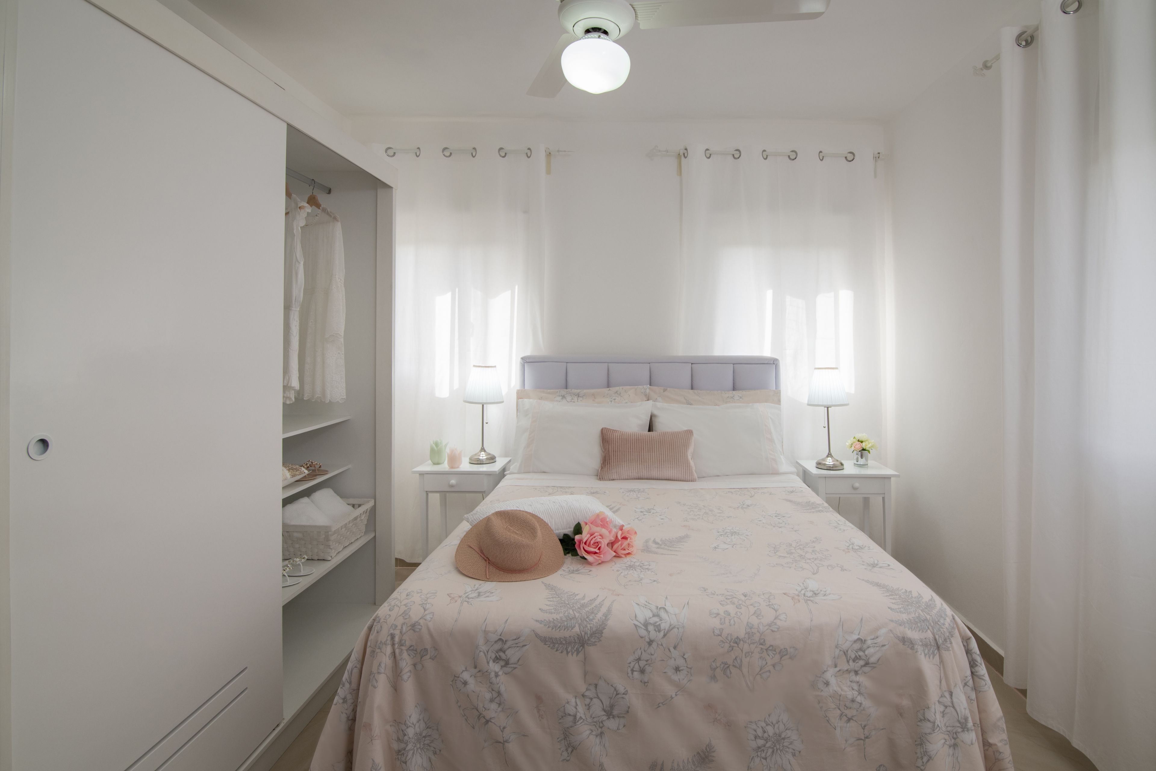 Een slaapkamer met een bed, nachtkastjes, een garderobe en een plafondventilator.