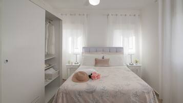Een slaapkamer met een bed, nachtkastjes, een garderobe en een plafondventilator.