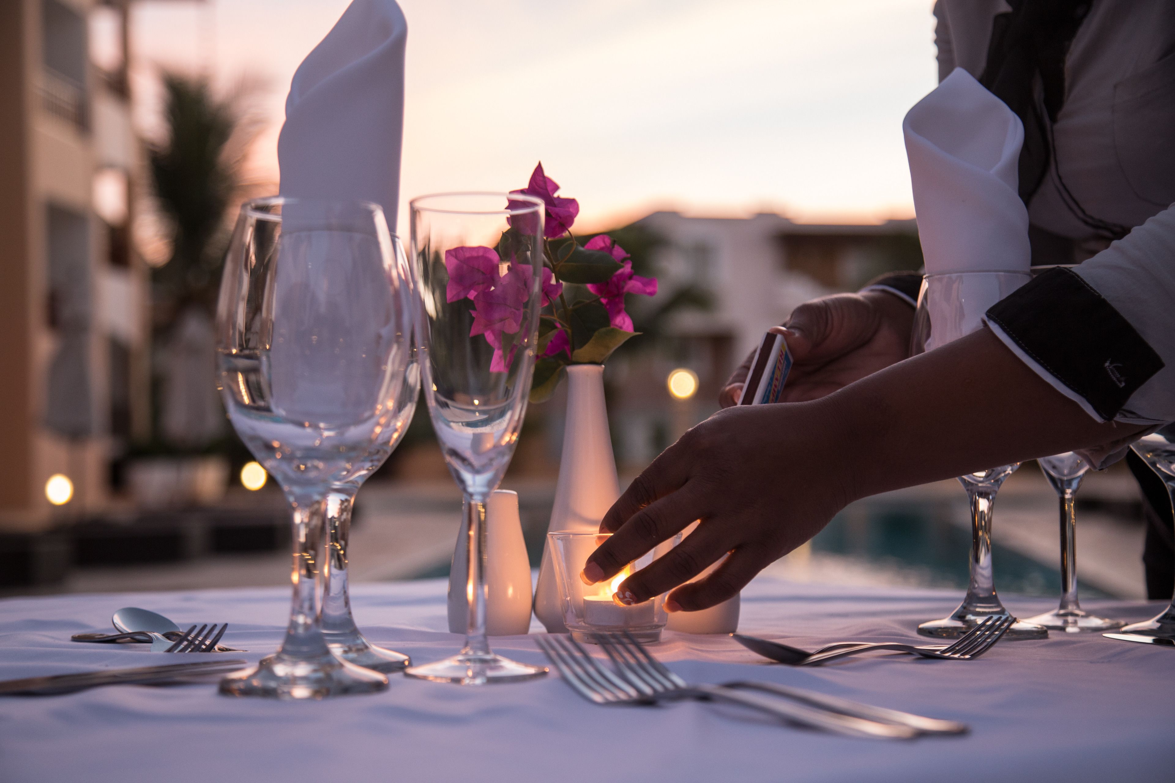 A table set for a meal with wine glasses, a candle, and a flower centerpiece.
