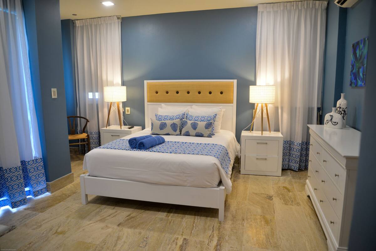 Un dormitorio con cama, mesitas de noche, cómoda y una silla.