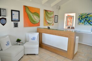 A reception area with a wooden reception desk, a white sofa with a logo, and artwork on the walls.