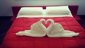 Un lit avec une couvre-lit rouge et deux serviettes en forme de cygne.