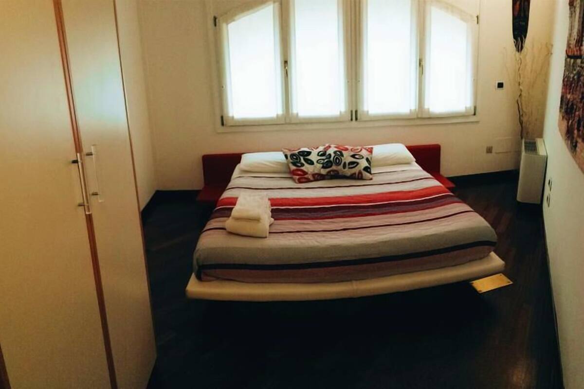 Een slaapkamer met een bed, een raam en een kledingkast.