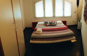 Un dormitorio con cama, ventana y armario.