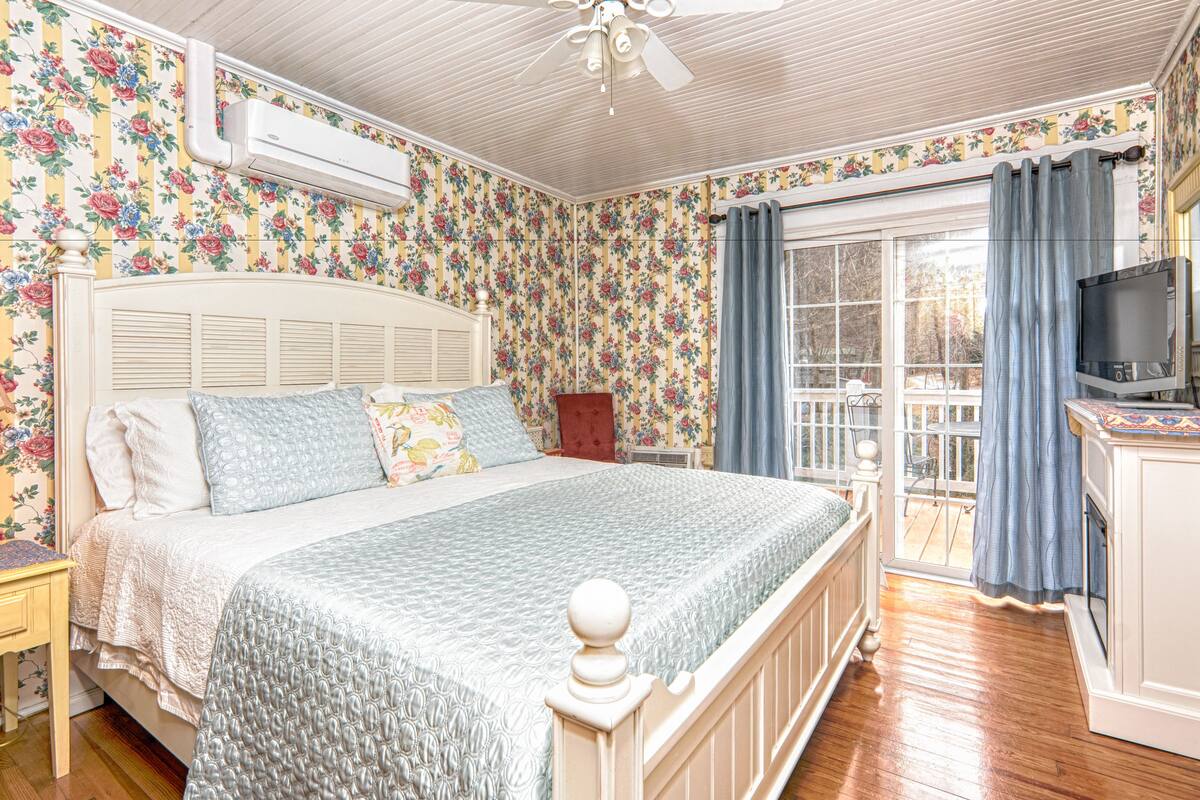 Un dormitorio con cama, televisor y ventana con cortinas.