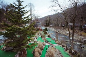 A house with a green golf course in the foreground and a river in the background. - Broad River Inn (Chimney Rock)