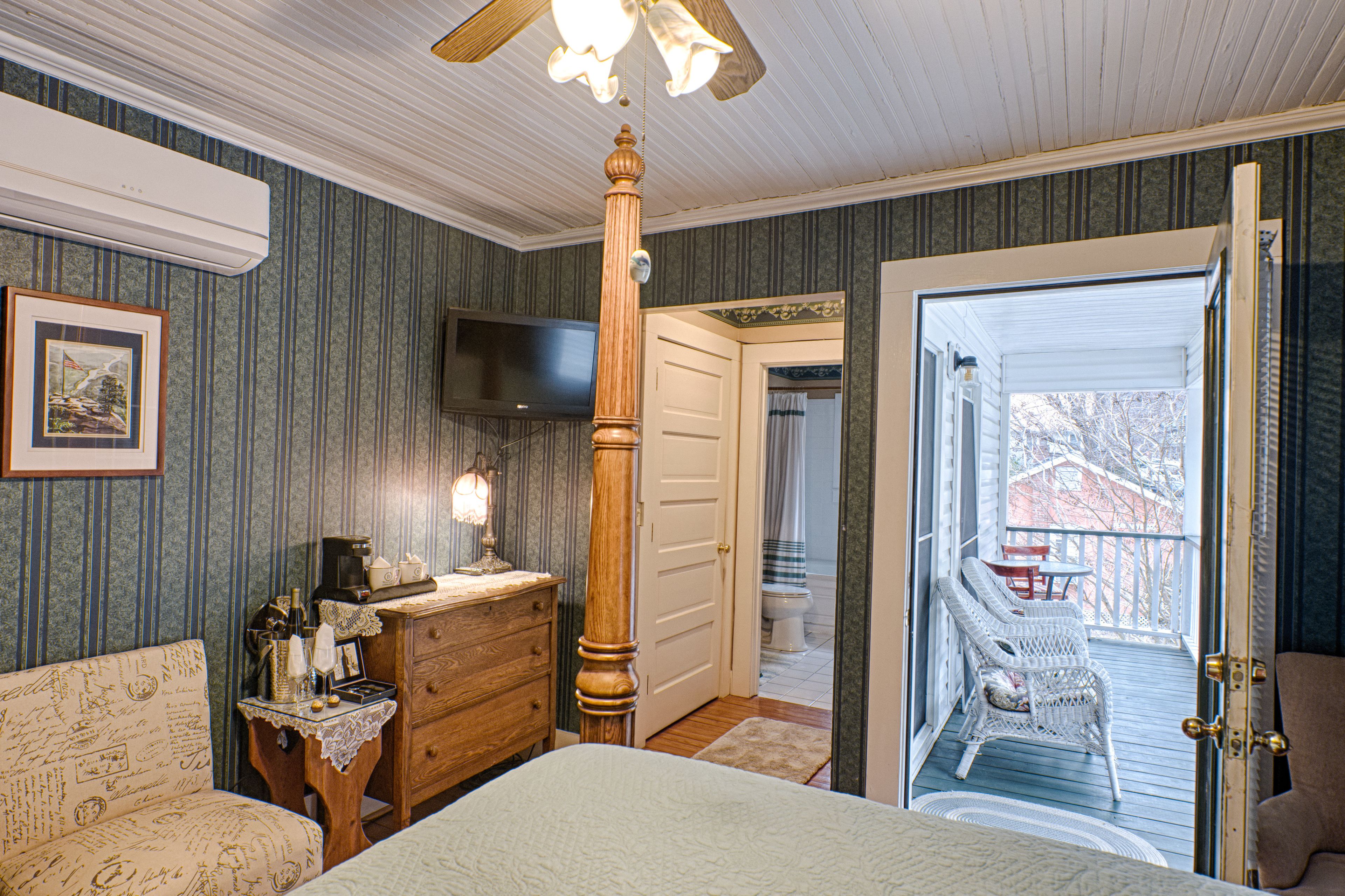 A bedroom with a bed, dresser, and a television on the wall.