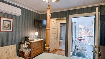 A bedroom with a bed, dresser, and a television on the wall.