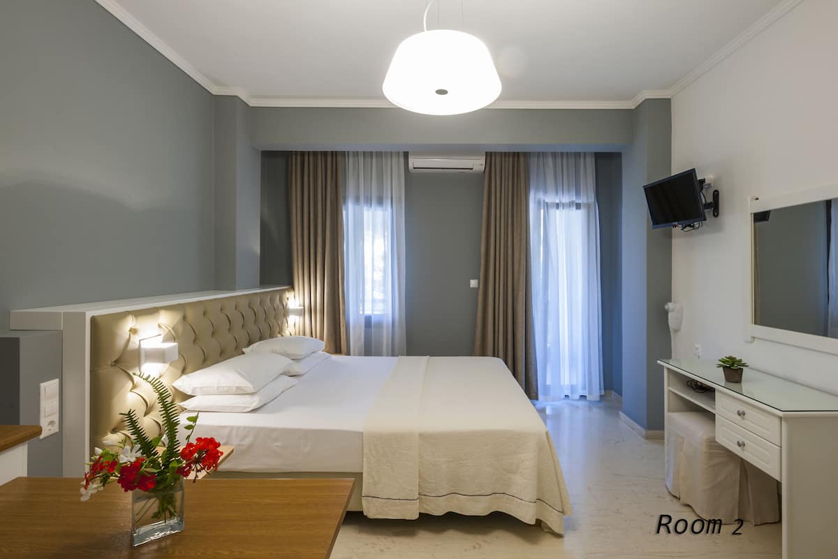 Ein Hotelzimmer mit Bett, Nachttisch und an der Wand befestigtem Fernseher.