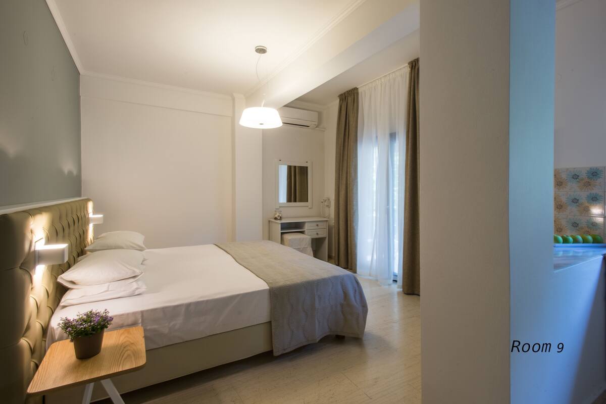 Ein ordentlich eingerichtetes Hotelzimmer mit Bett, Nachttisch, Lampe und einer kleinen Topfpflanze.
