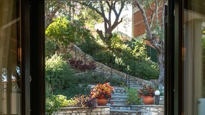 A room with a glass door leading to an outdoor patio with a stone wall, two chairs, and a small table.