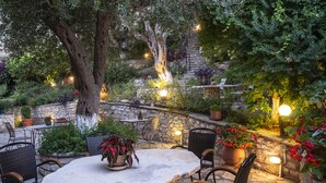 An outdoor patio with stone walls, potted plants, and outdoor furniture.
