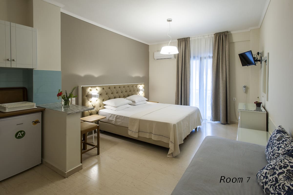 Ein Hotelzimmer mit Bett, Nachttisch, Schreibtisch und einer kleinen Küchenzeile.