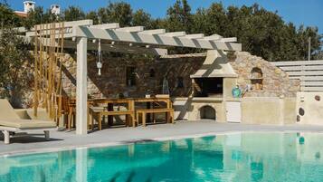 Relax by the serene pool surrounded by lush greenery and a shaded seating area.