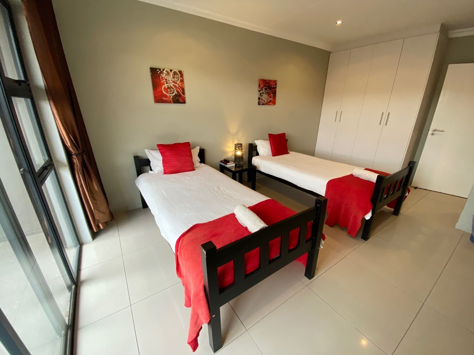 Habitación de hotel con dos camas, un armario y obras de arte en las paredes.