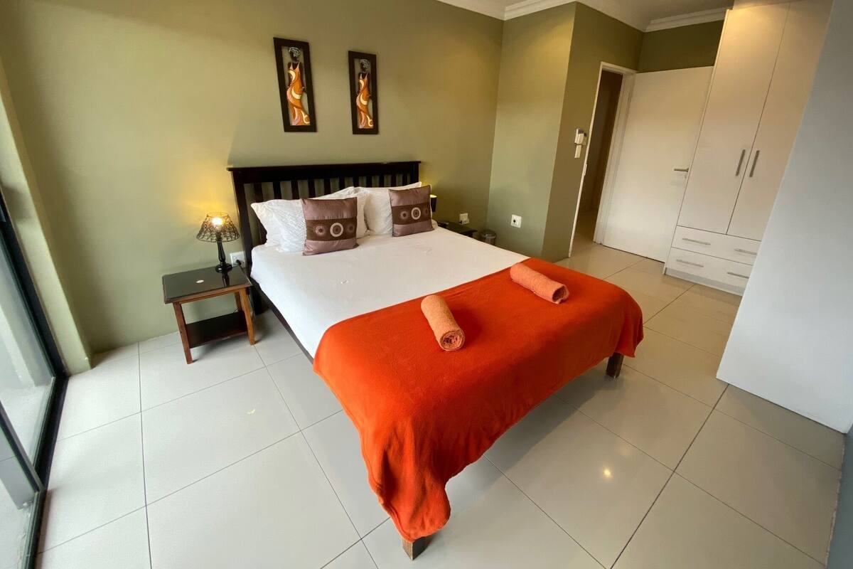 Habitación de hotel con una cama grande, una mesita de noche, un armario y dos marcos con cuadros colgados en la pared.