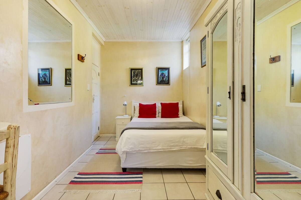 Quarto com cama, mesas de cabeceira, espelho e obras de arte nas paredes.