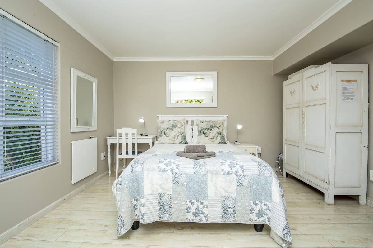 Quarto com cama, escrivaninha, cadeira, guarda-roupa e janela com persianas.