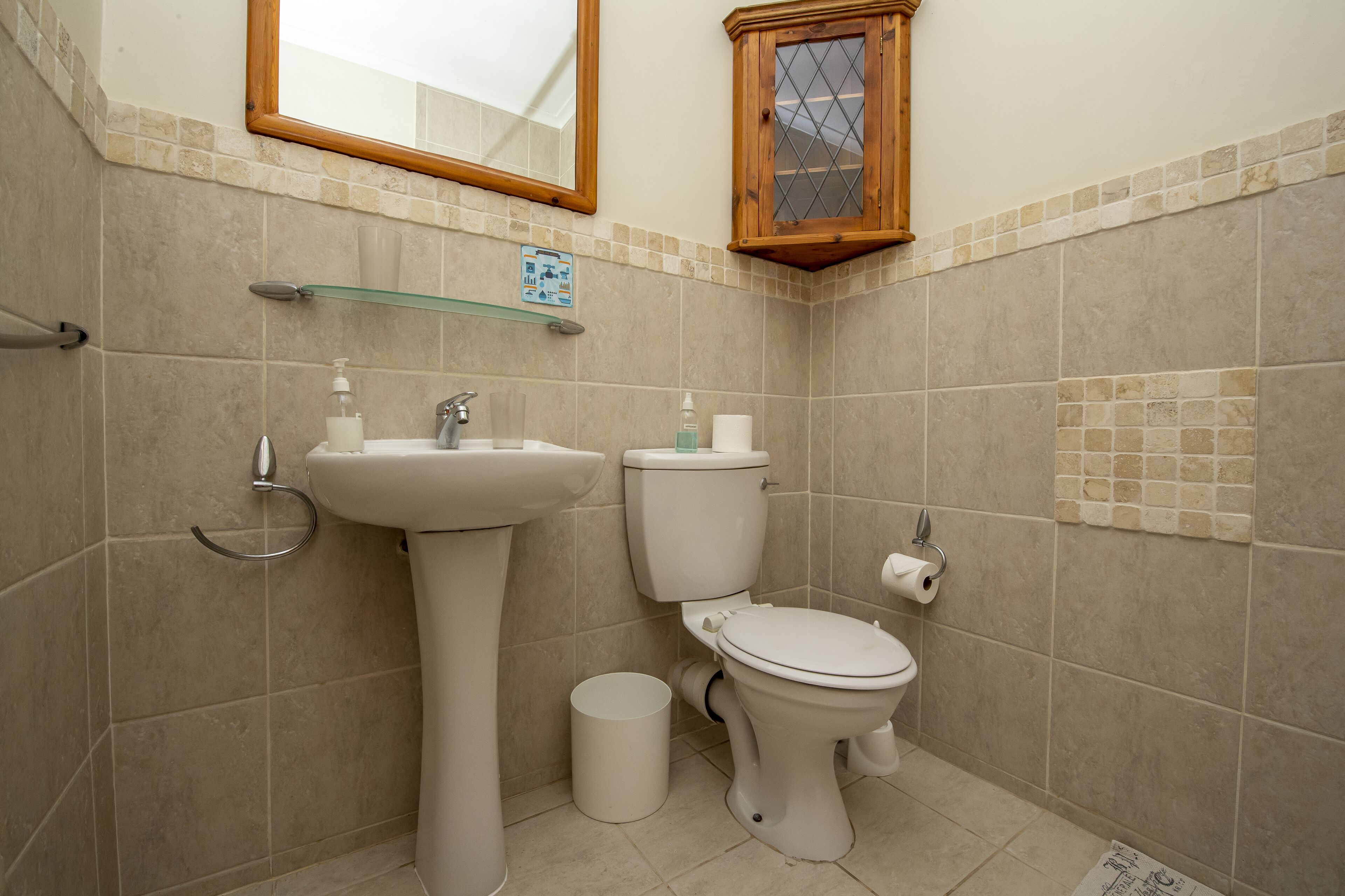 A bathroom with a sink, toilet, and mirror.