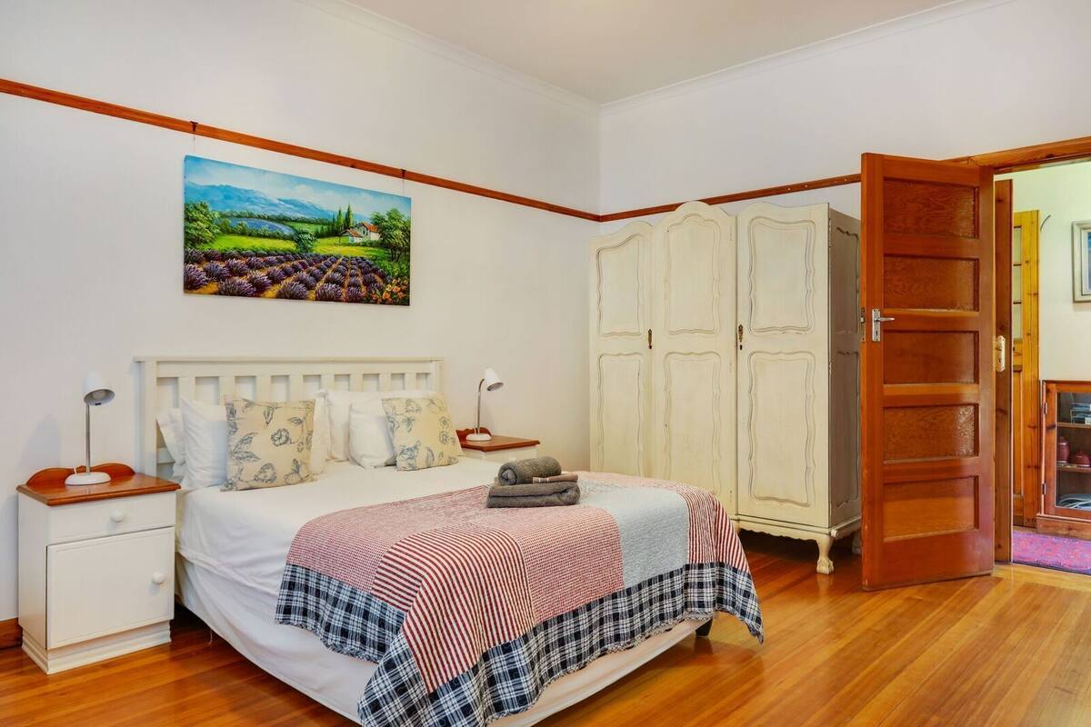 Quarto com cama, mesas de cabeceira, guarda-roupa e um quadro na parede.
