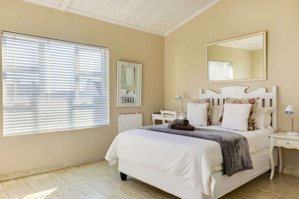 Quarto com cama, mesas de cabeceira, espelho e radiador.