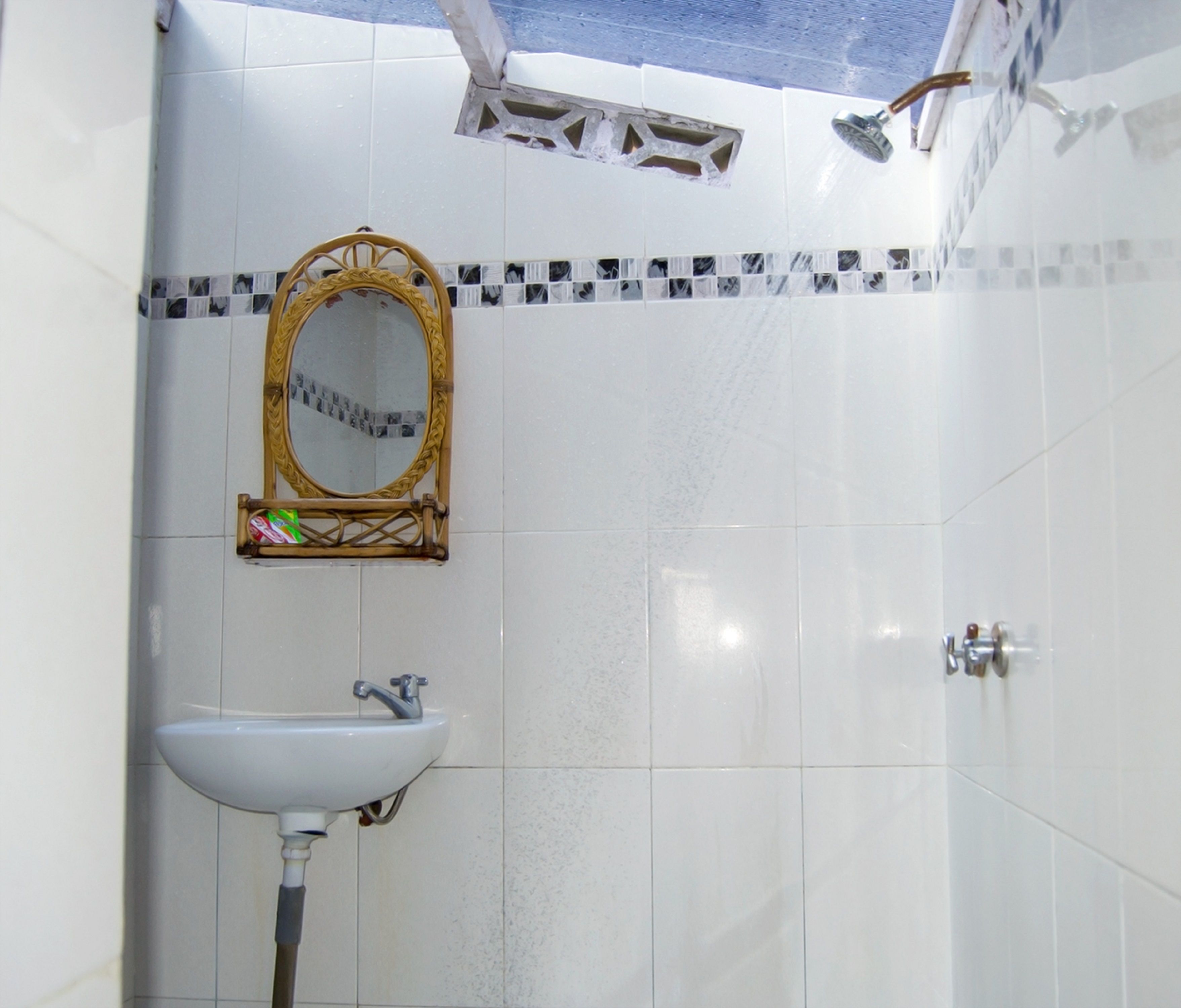 A bathroom with a white sink, a mirror with a decorative frame, and a shower area.